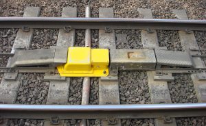 A yellow magnet shaped like a ramp sits in between the rails of a railway track