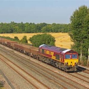 A British freight train moving through countryside along multiple tracks